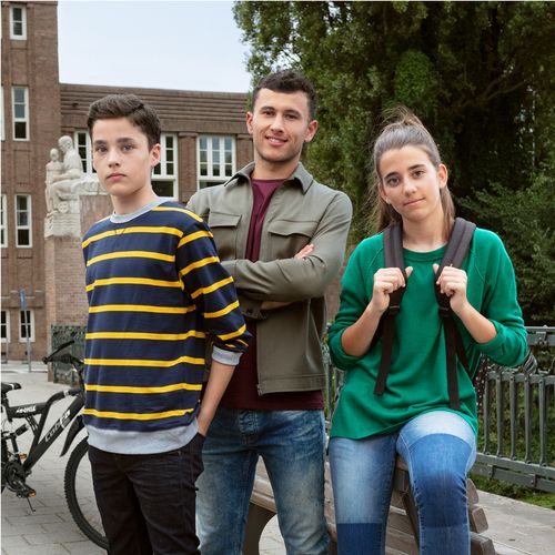 3 leerlingen staan geposeerd terwijl zij naar de camera kijken.