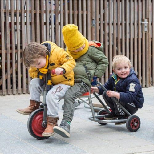 3 kinderen op een speelfiets.
